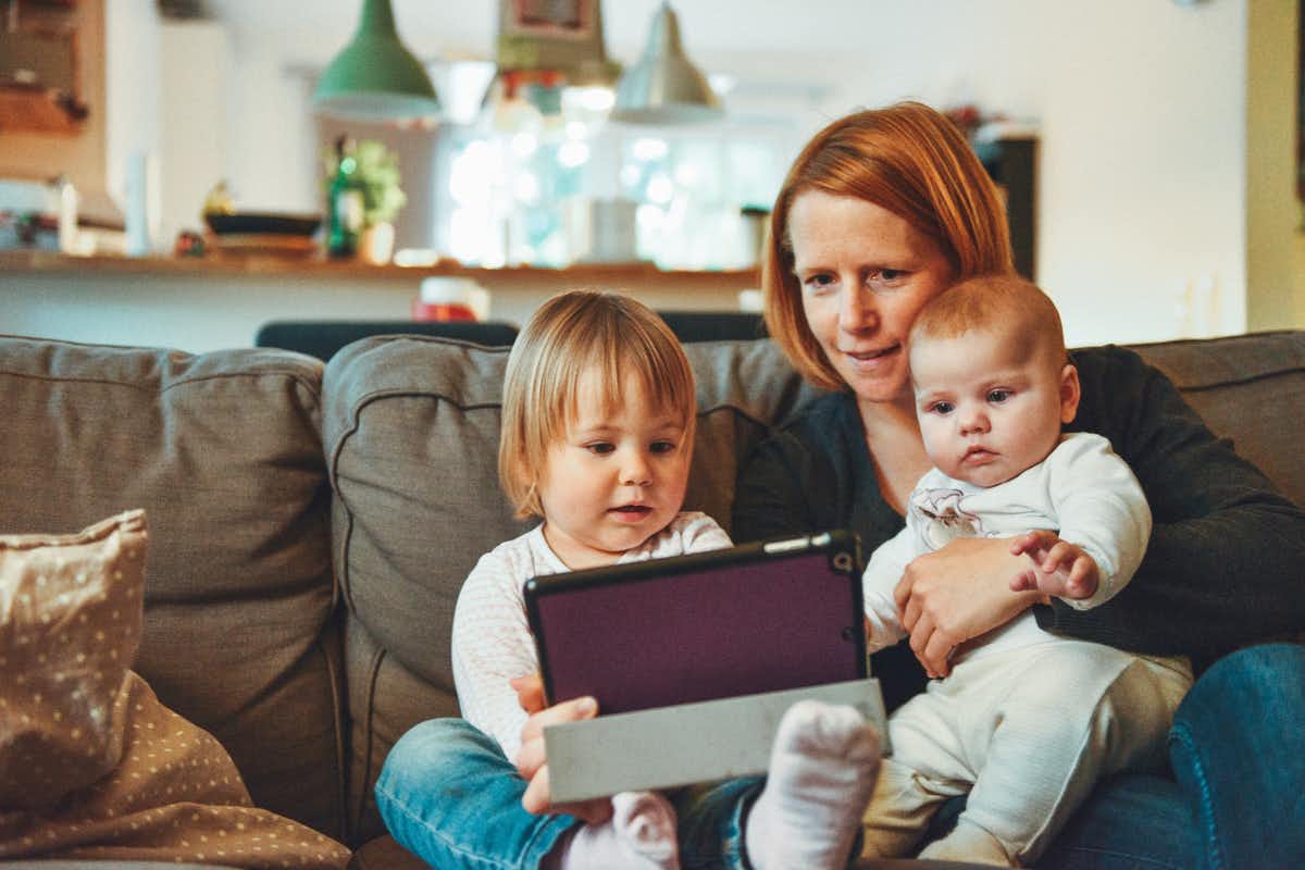 Mujer mirando un dispositivo con con sus hijos